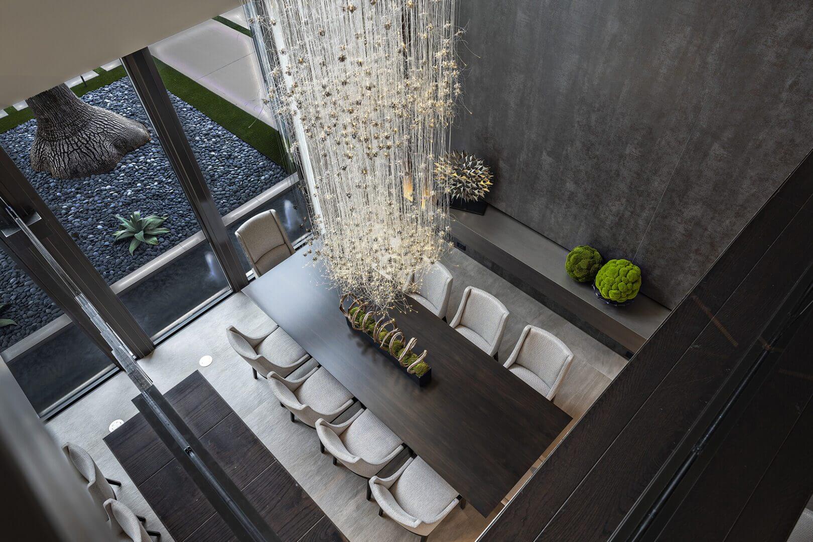 Modern dining room with large chandelier overhead.